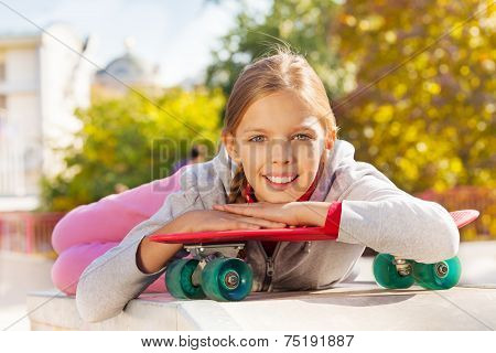 Beautiful young lady with arms on red skateboard
