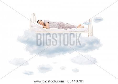 Young man sleeping on a comfortable bed in clouds isolated on white background