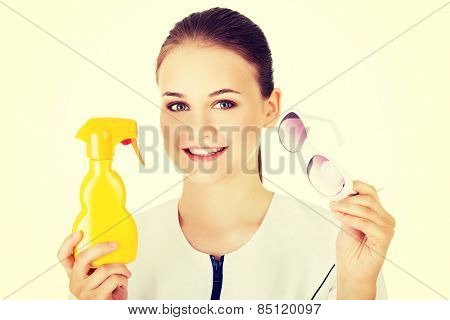 Woman doctor or nurse showing sunscreen and sunglasses.