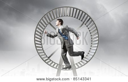 Young businessman running in huge hamster wheel