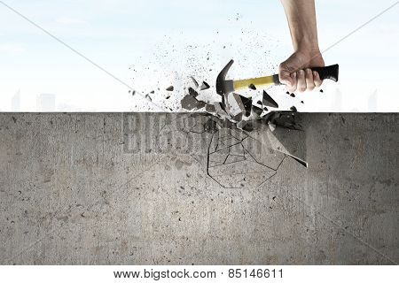 Close up of hammer in hand breaking cement wall