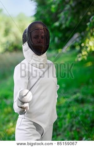 Fencer woman staying over beautiful nature background with rapier