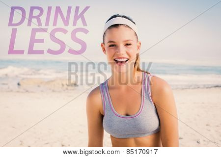 Sporty blonde on the beach smiling at camera against drink less