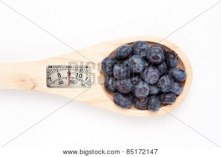 weighing scales against wooden spoon with blueberrry