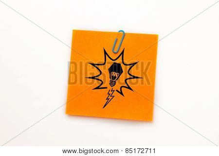 Light bulb against orange adhesive note with a paperclip