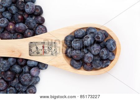 weighing scales against wooden spoon with blueberrry