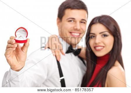 Man and his fiancee showing their engagement ring with the focus on the ring isolated on white background