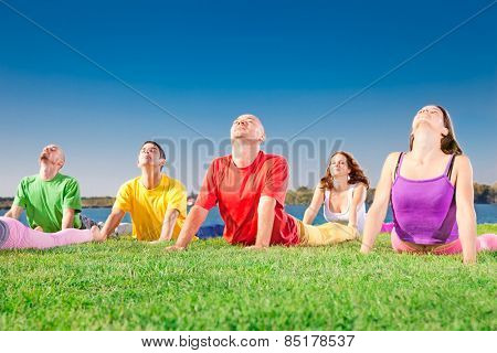 Young people practice Yoga asana on lakeside. Yoga concept.