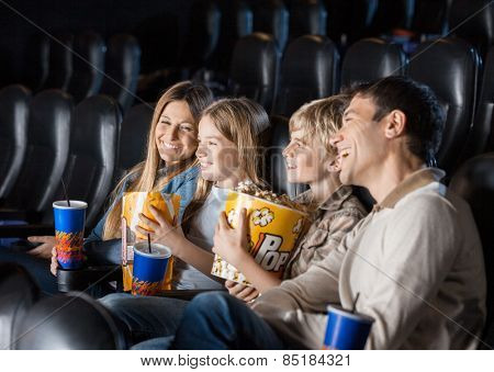 Cheerful family having snacks while enjoying movie in cinema theater