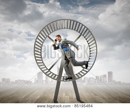 Young businessman running in huge hamster wheel