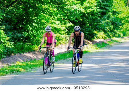 Young pair of professional cyclists riding on the road