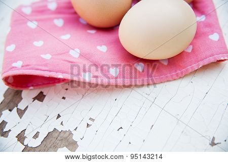 Eggs on tablecloth over wooden background