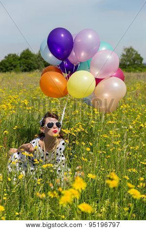 Pin Up Girl On A Flowery Meadow With Colorful Balloons