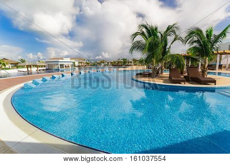 Cayo Guillermo island, Iberostar Playa Pilar hotel, Cuba, June 28, 2016, nice beautiful inviting view of a curved comfortable swimming pool with ceramic beds on blue sky background