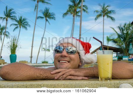 Man in Santa Claus Hat Relaxes by the Pool shot with a Sony a6300