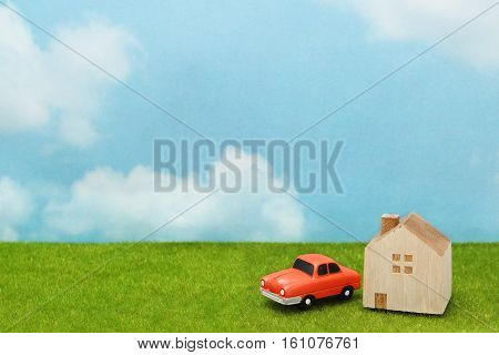 House and car on green grass over blue sky and clouds. My home and car concept.