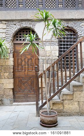cairo, Egypt - December 10, 2016: View of the courtyard of Beit El Set Waseela (Waseela Hanem House) showing a wooden closed door and window with interleaved wooden grid and stair with wooden handrail leading to the upper floor Medieval Cairo Egypt