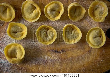 Freshly Prepared Italian Tortellini On Wooden Board Top View