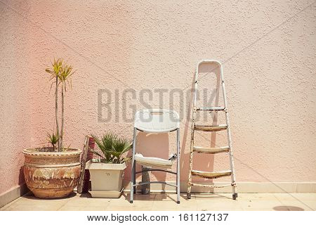 Mainstream fashion photo. Objects standing in a row stepladder chair pot on wall background