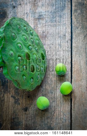 Three lotus seeds and calyx on wooden background