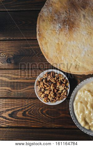 Top view of ingredients for baking homemade cake. shortcakes, buttercream or cream and nuts on a plate on vintage wooden kitchen table. copyspace for cook recipe. Vertical image