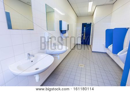 Toilet room for boys with urinals sinks and mirrors on high school