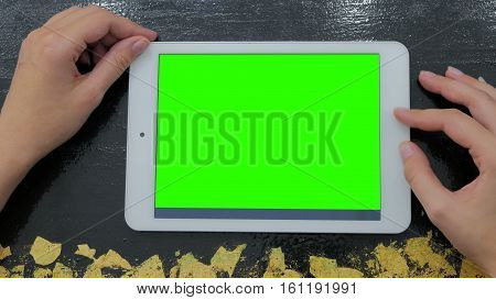 Woman looking at horizontal tablet computer with green screen. Close up shot of woman's hands with pad