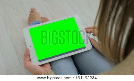 Woman looking at horizontal tablet computer with green screen. Close up shot of woman's hands with pad