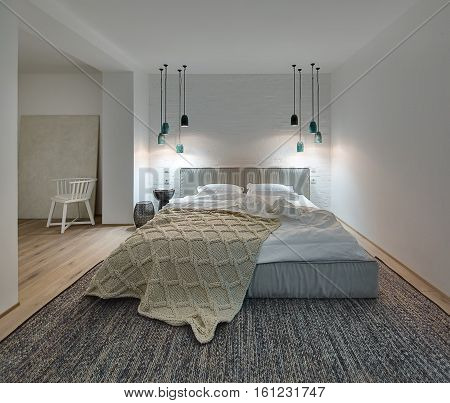 Bedroom in a modern style with white walls and a parquet with a carpet on the floor. There is a bed with a white pillows and blanket and brown plaid, nightstand with book and lampshade, lamps, chair.