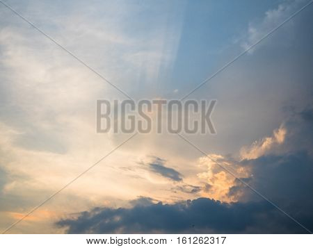 Picture of the sunset cloudy sky reflecting orange sun rays. Background of the sunset sky with sun rays reflecting from the clouds.
