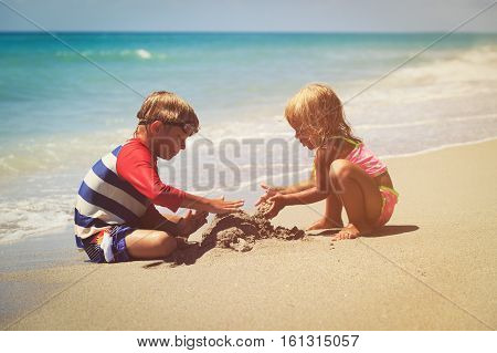 kids play with sand on summer tropical beach
