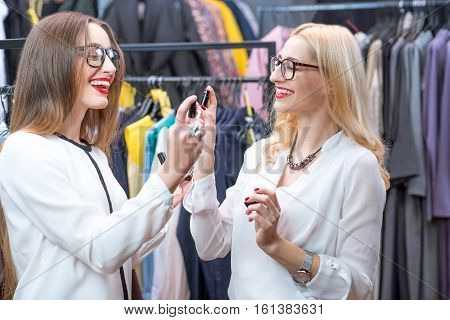 Beautiful women choosing perfumes in the clothing store