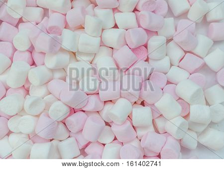 Pink and white mini marshmallows background close-up texture. A pile of different mini puffy marshmallows. Marshmallow concept. Wallpaper for desktop. Top view.
