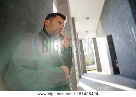 Businessman leaning on wall talking on phone