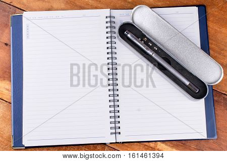 notebook with pen on old wooden table