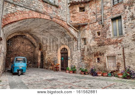 TODI, ITALY - SEPTEMBER 10: a picturesque old alley with dwellings and an ancient italian vehicle Ape Piaggio, on September 10, 2013 in Todi, Umbria, Italy
