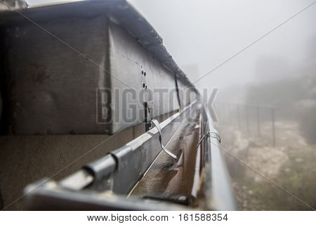 Gutter drainage system on the roof with dripping fog. Closeup