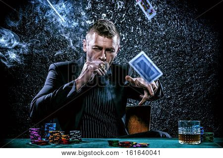 Excited gambling man throwing playing cards on a game table in a casino. Gambling, playing cards and roulette.