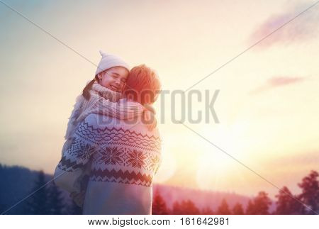 Happy loving family! Father and his daughter are playing and hugging outdoors. Cute little girl and daddy on snowy winter walk in nature. Concept of frost winter season.