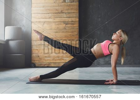 Young slim blond woman in yoga class making asana exercises. Girl do purvottanasana, upward plank pose. Healthy lifestyle in fitness club. Stretching