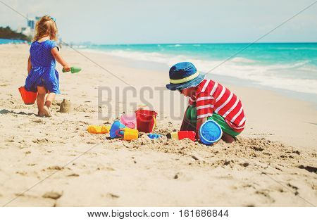kids play with sand on summer beach, family at beach