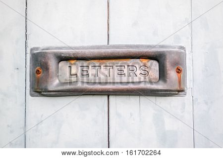 An old rustic letterbox on a wooden door