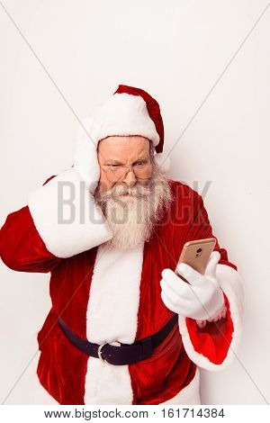 Confused Santa Claus Wearing Red Costume Reading Messege On Phone  While Standing White Background