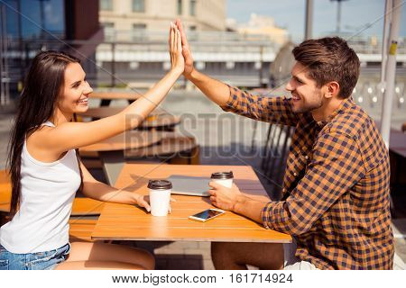 Happy Pretty Woman Giving High Five To Her Boyfriend In Cafe