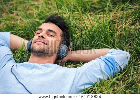 Upper view.Close-up portrait of young smiling man enjoying and dreaming with headphones listen the music