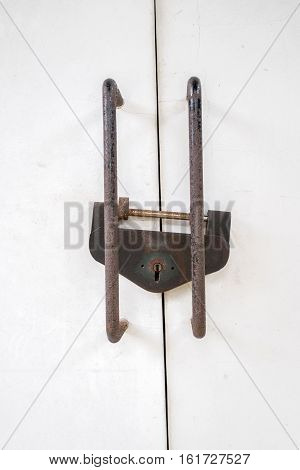 rusted metal lock on white doors with metal bars