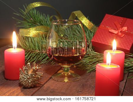 Brandy glass and candles on black background.