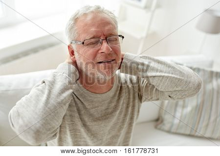 healthcare, pain, stress, age and people concept - senior man suffering from neckache at home