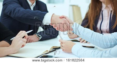 Male and female handshake in office. Serious business and partnership concept. Partners made deal sealed with handclasp.
