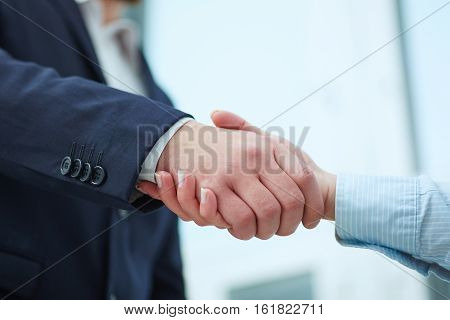 Male and female handshake in office. Businessman in suit shaking woman's hand. Serious business and partnership concept. Partners made deal and sealed it with handclasp. Formal greeting gesture.